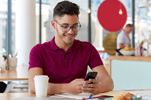 man smiling whilst looking down at phone